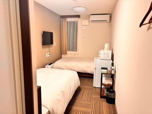 a hotel room with two beds and a tv at 未来ホテル MiraiHotel in Isesaki