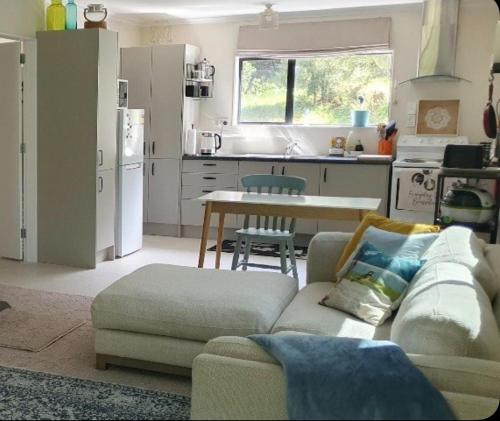 a living room with a couch and a table in a kitchen at Peaceful Rural Cottage in Kopuaranga