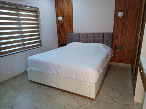 a white bed in a bedroom with a window at Oceanus Retreat in Mayyanād