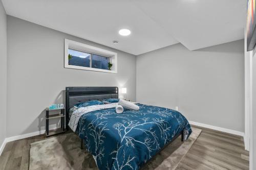 Un dormitorio con una cama con edredón azul y una ventana. en Peaceful 1BHK - Maple, en Edmonton