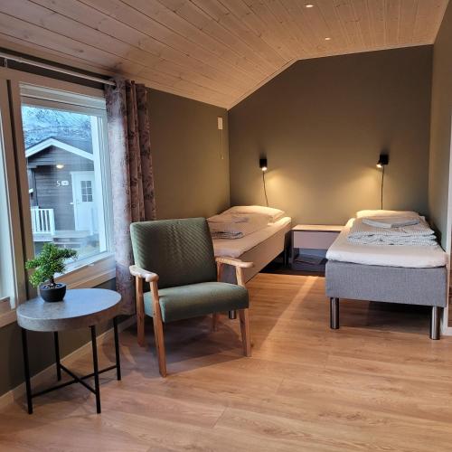 a room with two beds and a chair and a window at Lapphaugen Turiststasjon in Tennevoll
