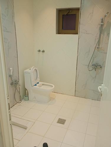 a white bathroom with a toilet and a shower at شقة مفروشه ومريحة وقريبه من المناطق السياحية عوائل فقط in Al Hulaylah