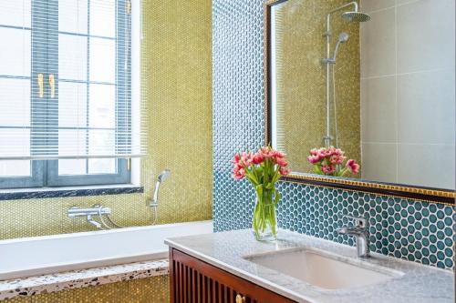 Misaki HCM Airport Hotel في مدينة هوشي منه: حمام مع حوض مع ورود في مزهرية