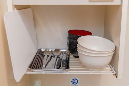 a shelf in a kitchen with bowls and utensils at 3 minutes walk from Minami Fukuoka Station, free Wi-Fi in Fukuoka