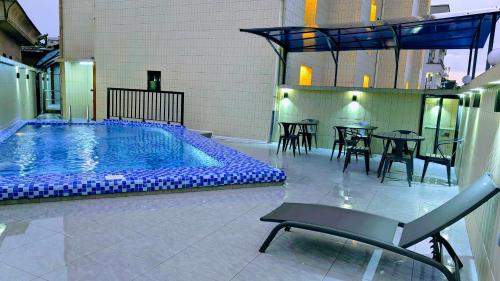 uma piscina com mesas e cadeiras e uma mesa e cadeiras em ALICIA HOTEL em Douala