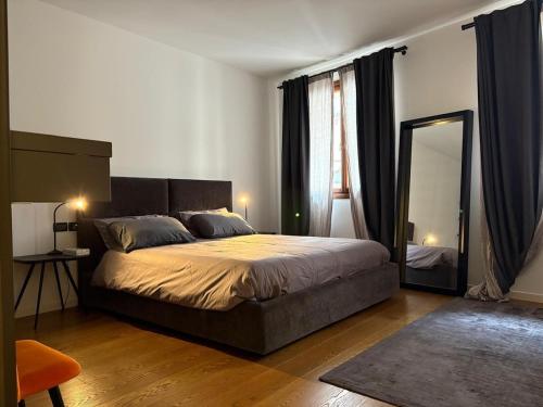 a bedroom with a large bed and a mirror at Elegante appartamento nel cuore di Bassano in Bassano del Grappa