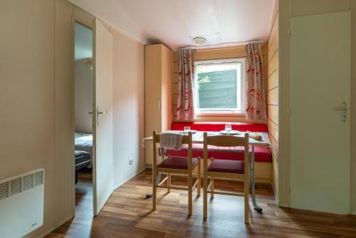Un pequeño comedor con una mesa y sillas rojas. en Camping Le Barutel, en Meyras