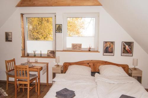 a bedroom with a bed and a table and two windows at Hof Bahrenwinkel in Osterholz-Scharmbeck