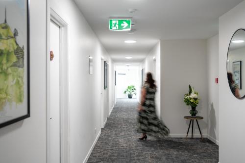 a woman walking down a hallway with a clock on the wall at Solsen Motel in Auckland