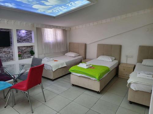 a room with three beds and a table and a red chair at OTEL 22 EDiRNE in Edirne