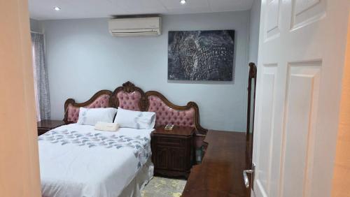 a bedroom with a bed and a wooden nightstand at Ntale Guest House in Benoni