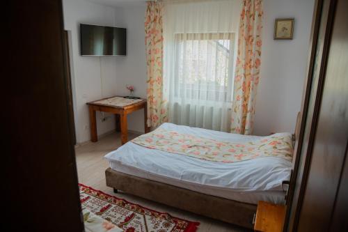 a small bedroom with a bed and a window at Craii Neamtului in Almaş