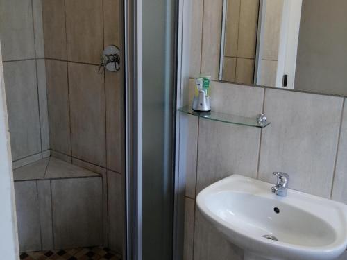 een badkamer met wastafel en douche met spiegel bij Twilight Inn in Vryheid