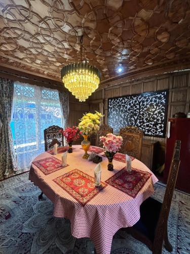 een eetkamer met een tafel met bloemen en een kroonluchter bij Houseboat Trambak in Srinagar
