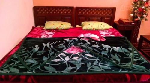 a bed with a red and black blanket and pillows at Star Rise Hotel in Naran
