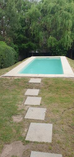 a swimming pool with stepping stones in the grass at Hermosa casa con piscina en Bella Vista Piriápolis a 2 c de la playa in Bella Vista