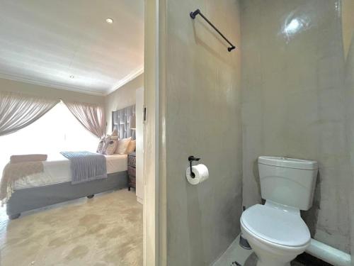 a bathroom with a toilet and a bedroom with a bed at OR Tambo Stay Unit 1 in Boksburg