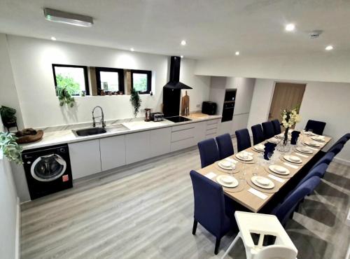 a kitchen and dining room with a long table and blue chairs at The Waltzing Weasel in Birch Vale