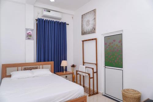 une chambre avec un lit et un rideau bleu dans l'établissement Aru Villa Galle, à Galle