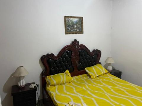 Un dormitorio con una cama con dos almohadas amarillas. en King's home, en Yaoundé