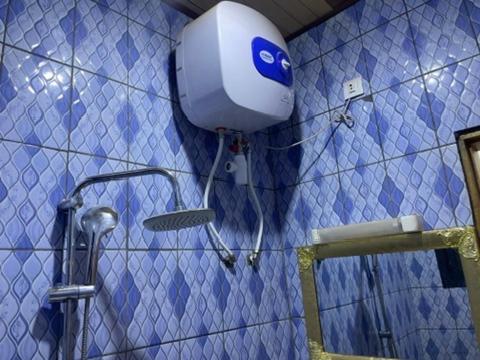 Un baño con azulejos azules, ducha y secador de pelo. en King's home, en Yaoundé