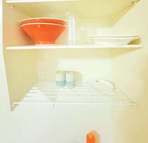 an open refrigerator with bowls and plates on shelves at Jaunty 130 Room 205 in Fukuoka