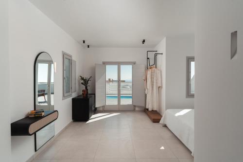 a white hallway with a bed and a mirror at Oikos Santorini Living Concept in Fira