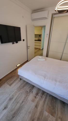 a bedroom with a white bed and a flat screen tv at Kings Apartments in Tiberias