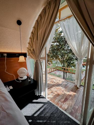 a bedroom with a bed and a deck with curtains at Nam garden lodge in Tân Phú