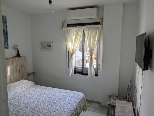 un dormitorio con una cama y una ventana en Casa Micho, en Tomares