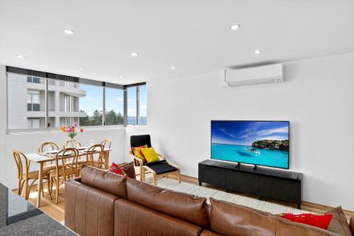 a living room with a couch and a tv at The Oceanfront Sanctuary Spa & Parking in Cronulla