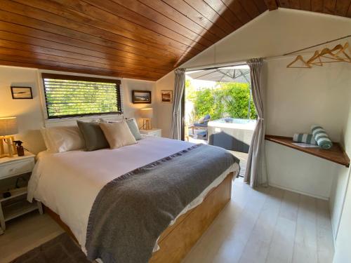 a bedroom with a bed and a window and a tub at Raglan View Cottage in Raglan