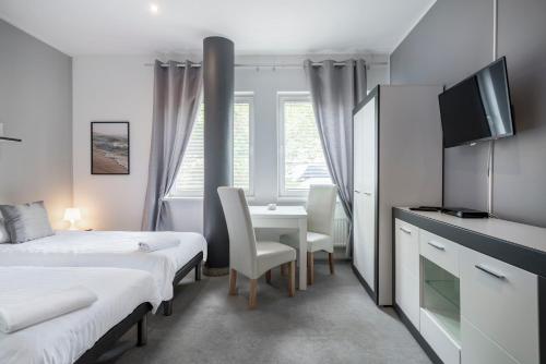 a room with two beds and a desk and a tv at Hostel Gdynia - Pokoje 2-osobowe na wyłączność in Gdynia