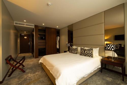 阿克拉Fiesta Residences Boutique Hotel and Serviced Apartments.的卧室里有一张白色的大床和一张书桌