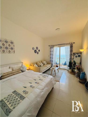 Un dormitorio con una cama grande y una sala de estar. en Bel Air -- Sea View Studio, en Ras al Khaimah