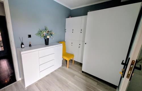 a room with a white cabinet and a yellow chair at Zajazd u George'a in Ziębice