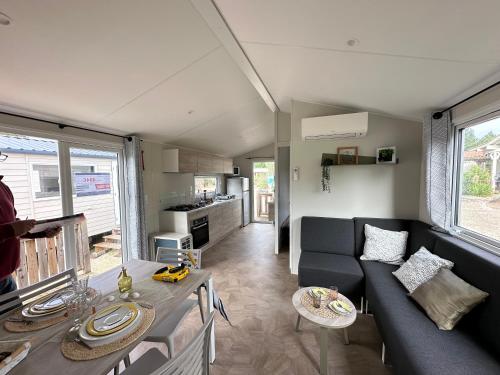 a living room with a couch and a table at Mobilhome neuf au camping La Réserve in Gastes