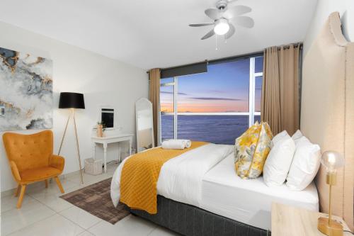 Un dormitorio con una cama y una ventana grande en Seaside Sunsets, en Strand