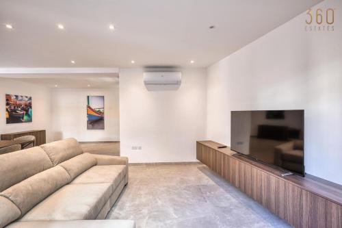 a living room with a couch and a flat screen tv at The Pender LUX HUB - 4BR villas with Pool, WIFI & AC by 360 Estates in St Julian's
