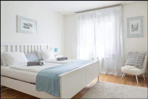 a white bedroom with a large bed and a chair at Cozy Apartment Ulmenstrasse in Luzern