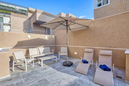 a patio with chairs and an umbrella on a building at The Pender LUX HUB - 4BR villas with Pool, WIFI & AC by 360 Estates in St. Julianʼs
