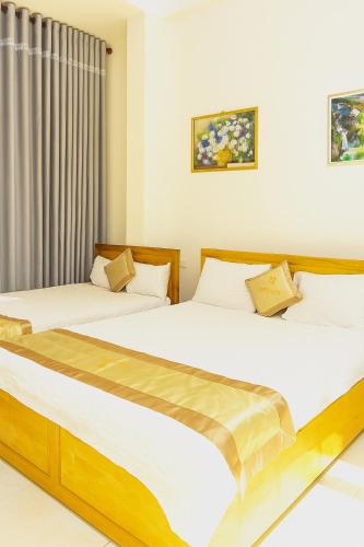 two beds in a room with white walls at Tấn Đạt Hotel Quy Nhơn in Quy Nhon