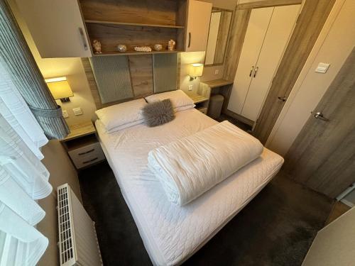 a large white bed in a small room at 64, Belle Aire Caravan Park, Sleeps 6, Bed Linen and Towels Included, Free WiFi, Pets Welcome with onsite clubhouse in Great Yarmouth