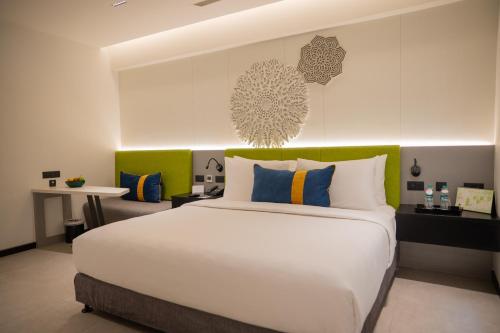 a bedroom with a large white bed with colorful pillows at ZIBE Luxe Kakinada by GRT Hotels in Kākināda