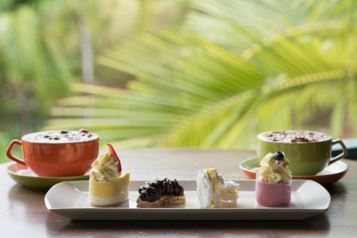 une assiette de desserts et deux tasses de café dans l'établissement Shingley Beach Resort - Whitsundays, à Airlie Beach