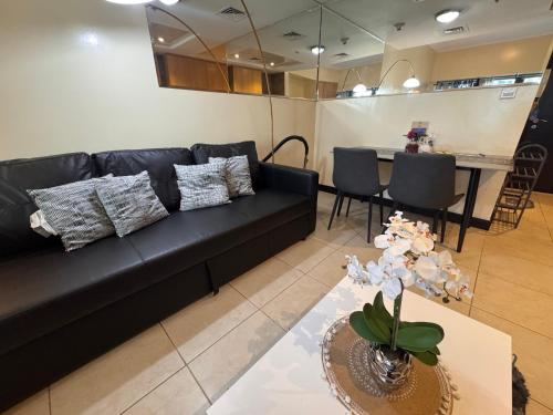 a living room with a black couch and a table at Click Stay - JLT - Studio & Balcony Lakes view Entire Apartment -JN in Dubai