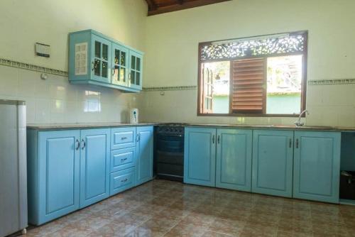 a large kitchen with blue cabinets and a window at Magnoon in Hikkaduwa