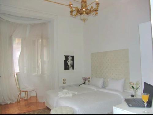 a white bedroom with a white bed and a chandelier at Qasr court in Cairo