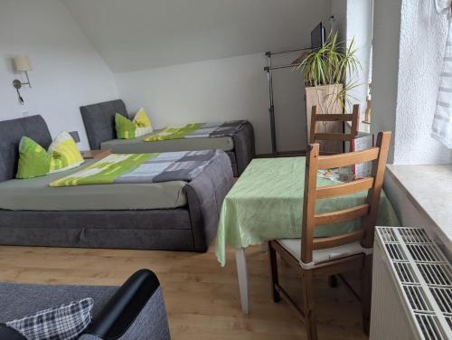 two beds in a room with a chair and a table at Pension Sommerfrische in Nebra