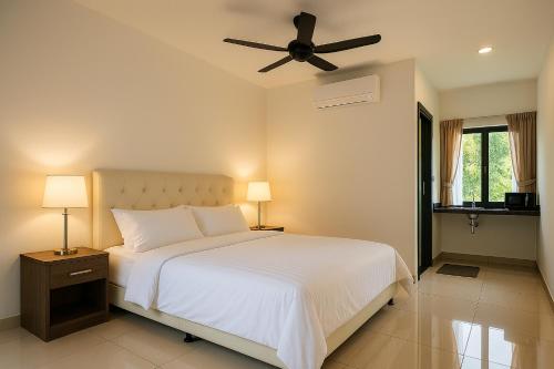 a bedroom with a white bed with a ceiling fan at Inap Keranji Homestay With Pool in Kota Bharu